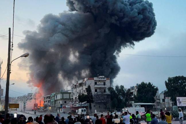 People gather as smoke billows near buildings following an Israeli strike after issuing an evacuation warning, in Toul, Nabatieh district, southern Lebanon, May 22, 2025. REUTERSpix