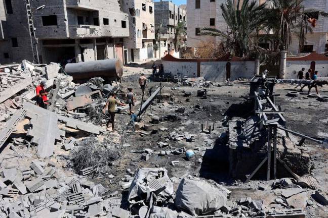 Palestinians gather amid the rubble near a fuel tank damaged in Israeli bombing, in Gaza City on September 14, 2024, amid the ongoing war between Israel and the Hamas militant group. - Omar AL-QATTAA / AFP