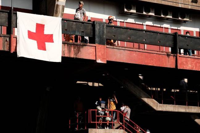 Civil defense members help a child as displaced people from recent clashes between armed groups take shelter at the General Santander Stadium in Cucuta, Norte de Santander Department, Colombia on January 19, 2025. A fresh outbreak of guerrilla violence amid a faltering peace process in conflict-riddled Colombia has left more than 80 people dead in just over three days, officials reported Sunday. The National Liberation Army (ELN) armed group launched an assault in the northeastern Catatumbo region last Thursday on a rival formation comprised of ex-members of the now-defunct FARC guerrilla force who kept fighting after it disarmed in 2017. - STR photographer / AFP