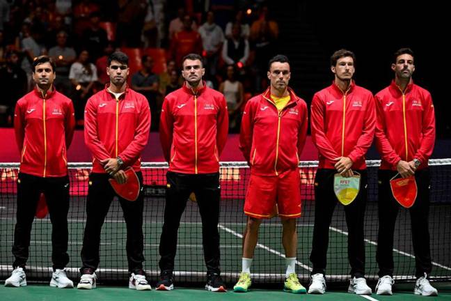 (From L) Spain's David Ferrer, Spain's Carlos Alcaraz, Spain's Pedro Martinez, Spain's Roberto Bautista Agut, Spain's Pablo Carreno Busta and Spain's Marcel Granollers line up before the group stage men's singles match between France and Spain of the Davis Cup tennis tournament at the Fuente San Luis Sports Hall in Valencia on September 13, 2024. - Jose Jordan / AFP