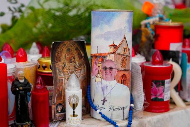 Candles, rosaries and messages are laid at the statue of John Paull II outside the Gemelli University Hospital where Pope Francis is hospitalized with pneumonia, in Rome. AFPpix