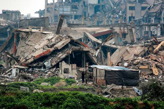 A man stands outside a shelter shack erected outside a collapsed building in the west of Beit Lahia in the northern Gaza Strip on February 11, 2025 amid the current ceasefire deal in the war between Israel and Hamas. - BASHAR TALEB / AFP