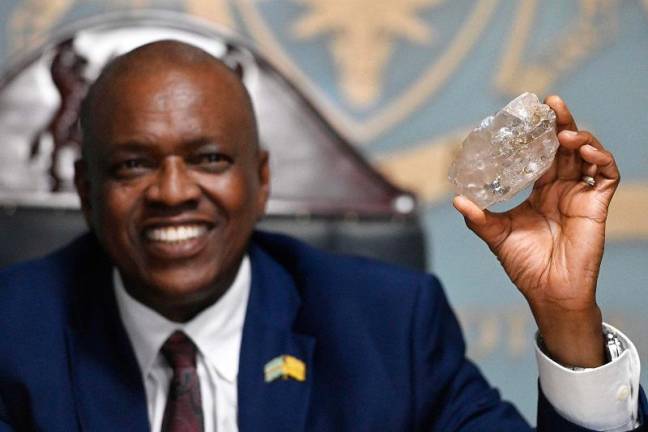 Botswana’s President Mokgweetsi Masisi holds a large diamond discovered in Botswana at his office in Gaborone on August 22, 2024. The 2492 carat diamond was discovered in the Karowe mine in Botswana of Lucara Diamond Company. Botswana is one of the world’s largest producers of diamonds, which constitute its main source of income, representing 30% of GDP and 80% of its exports. - (Photo by Monirul BHUIYAN / AFP)