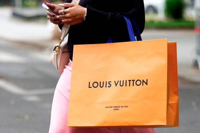 A woman walks with a Louis Vuitton shopping bag in Paris, France, April 17, 2025. - REUTERSpix