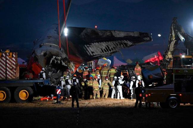 Firefighters and rescue personnel carry the body of a victim near the scene where a Jeju Air Boeing 737-800 series aircraft crashed and burst into flames at Muan International Airport in South Jeolla Province, some 288 kilometres southwest of Seoul on December 29, 2024. A Jeju Air plane carrying 181 people from Thailand to South Korea crashed on arrival, smashing into a barrier and bursting into flames, leaving all but two feared dead. - Jung Yeon-je / AFP