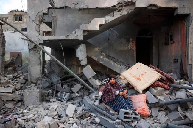 A woman sits on the rubble of her home, destroyed in an Israeli strike, at the Nuseirat refugee camp in the central Gaza Strip on March 18, 2025. Israel on March 18 unleashed its most intense strikes on the Gaza Strip since a January ceasefire, with rescuers reporting 220 people killed, and Hamas accusing Benjamin Netanyahu of deciding to “resume war” after a deadlock on extending the truce. - Eyad BABA / AFP