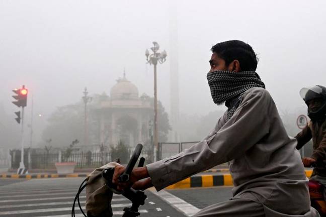 Commuters ride along a street engulfed in smog in Lahore on November 14, 2024. Lahore -- a city of 14 million people stuffed with factories on the border with India -- regularly ranks among the world's most polluted cities, but it has hit record levels this month. - Arif ALI / AFP