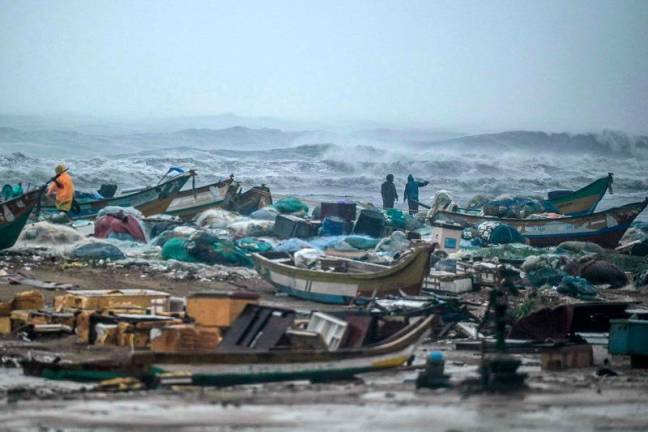 Fishermen pull their boats at Marina Beach amid heavy winds and rainfall in Chennai on November 30, 2024, ahead of the landfall of cyclone Fengal in India's state of Tamil Nadu. Cyclonic storm Fengal is forecast to make landfall in Tamil Nadu state with sustained winds of 70-80 kilometres an hour (43-50 mph) in the afternoon, India's weather bureau said. - R. Satish BABU / AFP