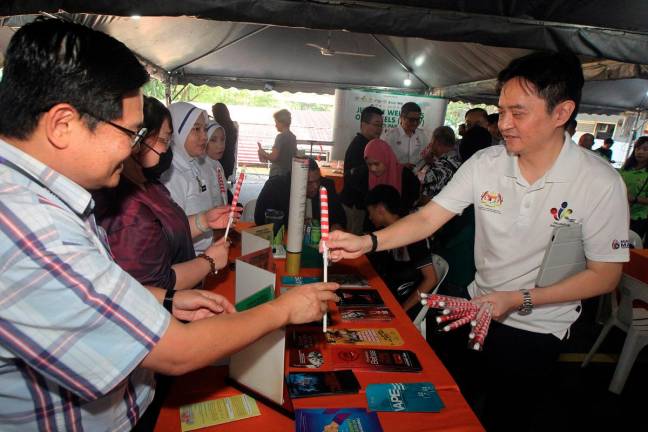 Ben Fong Kok Seng handing over Jalur Gemilang to folks during a recent event. - Pic courtesy of Ben Fong Kok Seng