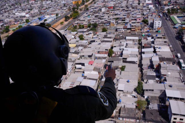 A member of Ecuadorian Army throws pamphlets from a helicopter with a telephone number to report criminal activity in Duran, Ecuador on June 13, 2025, as part of an initiative financially supported by the United States Southern Command to combat crime. - AFPpix