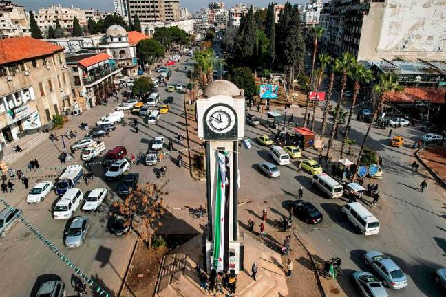 This aerial view shows traffic around the New Clock Tower along Quwatli Street in the Shayah district of Homs on December 16, 2024. Islamist-led rebels took Damascus in a lightning offensive on December 8, ousting president Bashar al-Assad and ending five decades of Baath rule in Syria. - Aaref WATAD / AFP