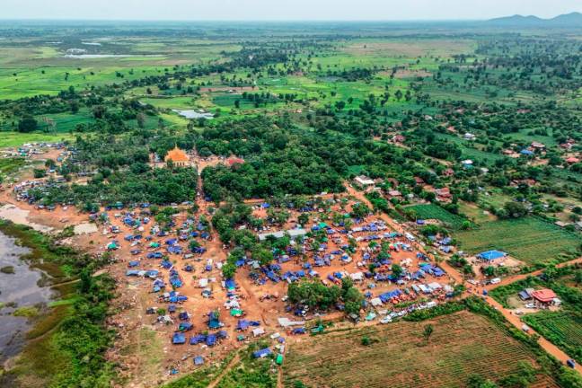 An aerial view shows people, who fled their homes near the border area between Cambodia and Thailand, taking shelter near a pagoda in Oddar Meanchey province on July 26, 2025. - AFP