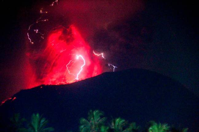 In this handout picture taken and released on June 6, 2024 by the Geological Agency lightning struck as lava erupts from the crater of Mount Ibu, as seen from West Halmahera, North Maluku. - AFP PHOTO / Geological Agency