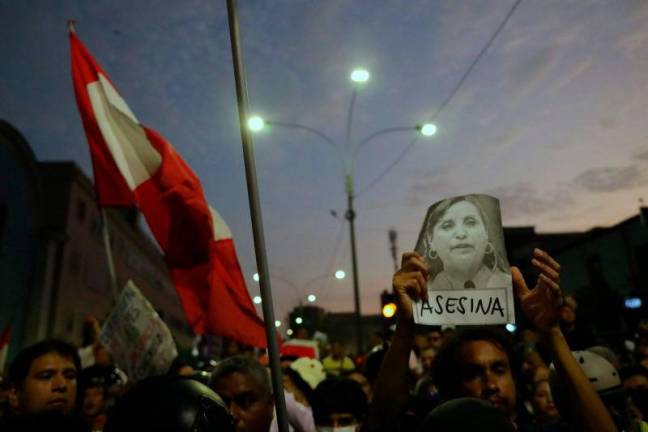 A demonstrator holds up a picture of Peru’s President Dina Boluarte reading “Murderer” during a national march against organized crime and hired assassinations called by social and political organizations in Lima on March 21, 2025. AFPpix