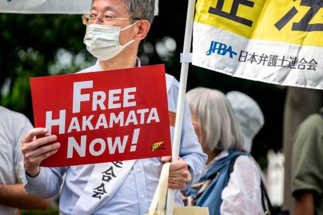 A man holds a sign reading “Free Hakamada Now!” outside the Shizuoka District Court on September 26, 2024. AFP