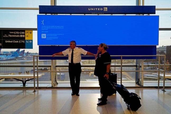 United Airlines employees wait by a departures monitor displaying a blue error screen, also known as the “Blue Screen of Death” inside Terminal C in Newark International Airport, after United Airlines and other airlines grounded flights due to a worldwide tech outage caused by an update to CrowdStrike's Falcon Sensor software which crashed Microsoft Windows systems, in Newark, New Jersey, U.S., July 19, 2024. REUTERS/Bing Guan