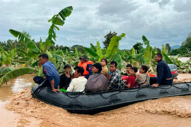 Residents are transported on a boat through flood waters in Sin Thay village in Pyinmana, in Myanmar's Naypyidaw region, on September 13, 2024, following heavy rains in the aftermath of Typhoon Yagi. Typhoon Yagi brought a colossal deluge of rain that has inundated a swathe of northern Vietnam, Laos, Thailand and Myanmar, triggering deadly landslides and widespread river flooding. - Sai Aung MAIN / AFP