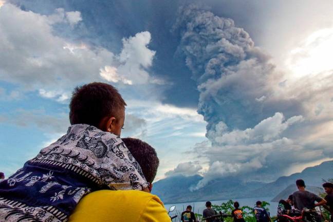 Residents watch the eruption of Mount Lewotobi Laki Laki from Eputobi village in Titihena, East Nusa Tenggara, on November 8, 2024. - Bayu ISMOYO and ARNOLD WELIANTO / AFPpix