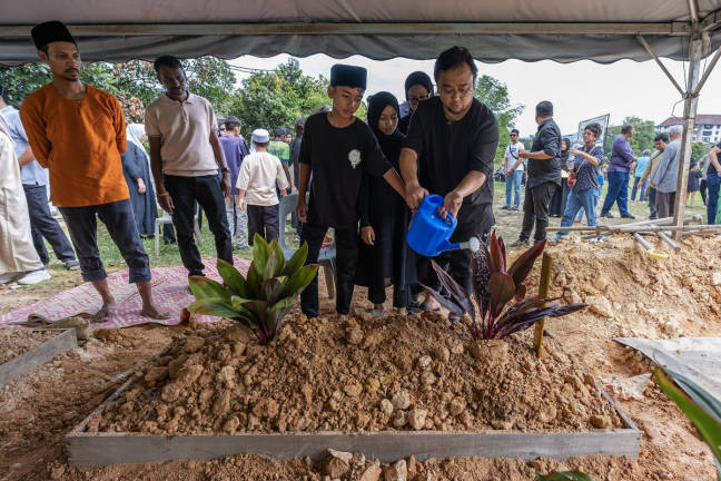 Family members poured water on the grave of Muhammad Khairy Nunis Abdullah, also known as Kevin Christopher Nunis, after he was laid to rest at the Taman Sri Sinar Segambut Muslim Cemetery today. - BERNAMA