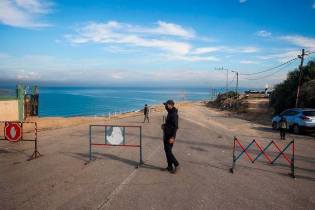 An armed man stands guard at a roadblock on Salah al-Din Street in Nuseirat on January 25, 2025. Israel said on January 25 it would block the return of displaced Palestinians to their homes in northern Gaza until civilian woman hostage Arbel Yehud is released. - Eyad BABA / AFP