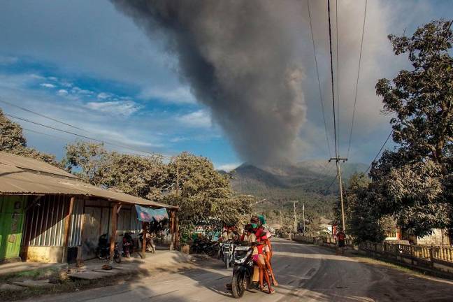 Villagers flee during an eruption of Mount Lewotobi Laki-Laki, a day after the previous eruption, in Boru Village, in East Flores, East Nusa Tenggara, on November 5, 2024. A volcano in eastern Indonesia erupted overnight, killing at least 10 people as it spewed fireballs and ash on surrounding villages, officials said on November 4 as they raised the alert to its highest level. - ARNOLD WELIANTO / AFP