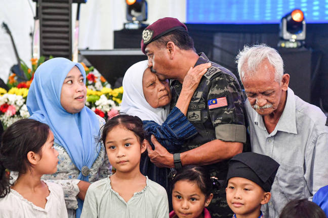 The Inspector-General of Police, Tan Sri Razarudin Husain (second from right), kissed his mother, Rahmah Ab Raman’s forehead during a photo session with close family members at the MADANI Adopted Village Community Harmony Program at Kompleks Institut Pengajian Tasauwuf today.