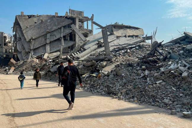 FILEPix: Palestinians walk past the rubble of destroyed houses. REUTERSpix