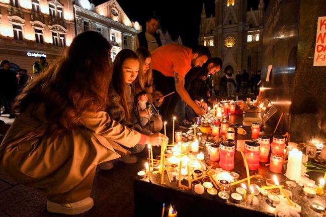 People light up candles in the city centre of Novi Sad, on November 1, 2024, following an accident at the main train station in Novi Sad, leaving at least 14 people killed and several people injured, according to emergency services in the area. At least 14 people were killed on November 1, 2024 after part of an outdoor roof collapsed at a train station in the Serbian city of Novi Sad, the president said. - NENAD MIHAJLOVIC / AFP