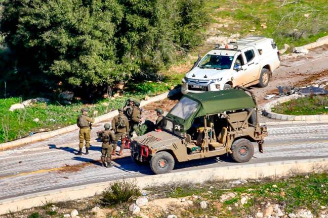 This picture taken from Lebanon's southern village of Shaqra on January 25, 2025 shows Israeli army soldiers by a humvee and a four-wheel-drive vehicle at the entrance of the village of Hula along the border with Israel in south Lebanon. - AFPpix