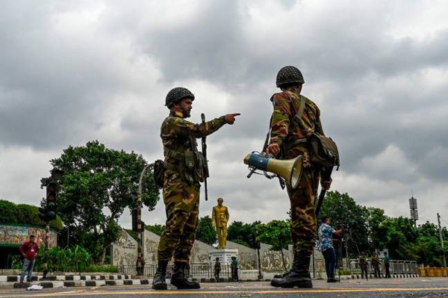 Bangladesh soldiers stand guard along the road following a curfew and the deployment of military forces in Dhaka on July 20, 2024, after days of clashes during protests against government job quotas across the country. Soldiers were out in force on July 20 in cities around Bangladesh after another day of lethal clashes between student protesters and police prompted Prime Minister Sheikh Hasina to cancel foreign visits. - AFPpix