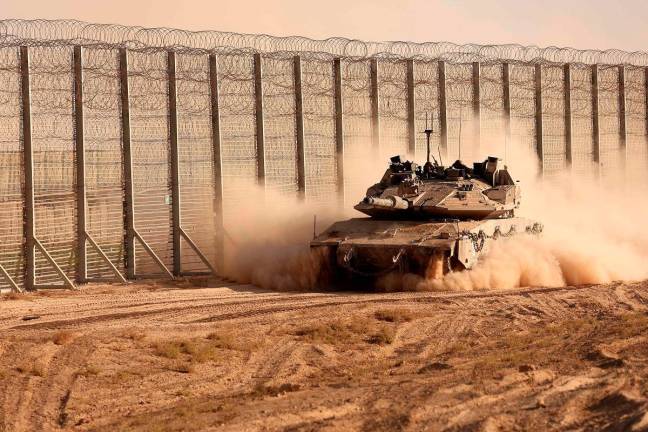 An Israeli army tank moves along the border fence between Israel and the Gaza Strip on October 21, 2025. Israel said on October 20 it had received the remains of another missing hostage from Gaza as part of a US-brokered ceasefire deal that came into effect on 10 October. - AFP