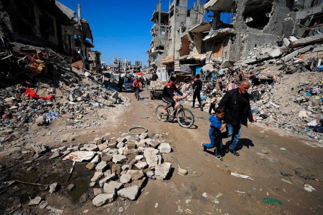 - Palestinians pass by the rubble of destroyed houses, in Gaza City, March 11, 2025. REUTERS/Dawoud Abu Alkas