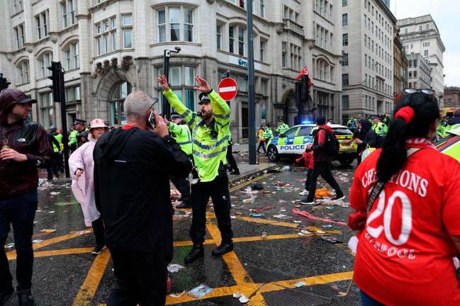 A Police officer shouts at Liverpool fans as he stands on duty a t a Police cordon at the entrance to Water Street, at the scene of an incident, on the sidelines of an open-top bus victory parade for Liverpool’s Premier League title win, in Liverpool, north-west England on May 26, 2025. - Darren Staples / AFP