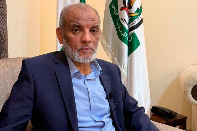 Hamas political bureau member Hossam Badran listens to a question during an interview with AFP in Doha on October 11, 2025. Badran predicted difficult negotiations ahead, suggesting the key question of disarmament could be a sticking point for the Palestinian militant group. - AFP