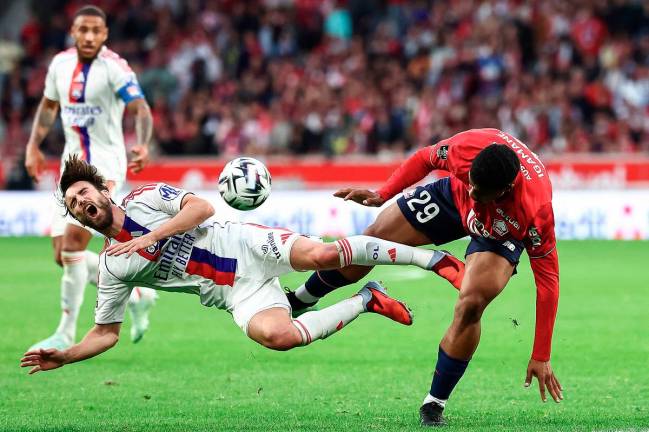 Lyon’s defender Nicolas Tagliafico (L) falls as he fights for the ball with Lille’s forward Hamza Igamane (R) during the French L1 football match between Lille LOSC and Olympique Lyonnais (OL) at the Stade Pierre-Mauroy in Villeneuve-d’Ascq, northern France, on September 28, 2025. - AFP