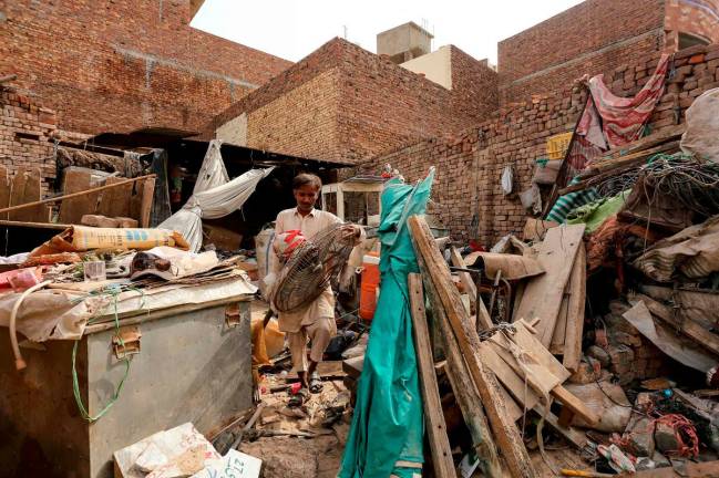 A man clears the remains of a damaged house, a day after strong winds, thunder and lightning in Multan on May 25, 2025. “Destructive” windstorms that raged across central and northern Pakistan after an intense heatwave have killed at least 14 people and injured over 100 more, officials said on May 25. - Shahid Saeed MIRZA / AFP