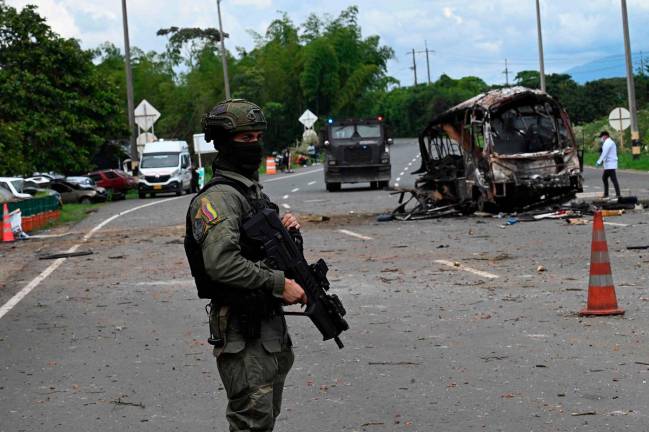 A police officer stands guard at the site where a bus exploded in front of a police station in Villa Rica, Cauca department, Colombia, on June 10, 2025. Southwest Colombia was rocked by a string of explosions and gun attacks that left at least three people dead Tuesday, police said, in what appeared to be a coordinated attack designed to sow terror. The attacks hit Cali -- the country’s third largest city -- and several nearby towns, targeting police stations and other municipal buildings. - Joaquin Sarmiento / AFP