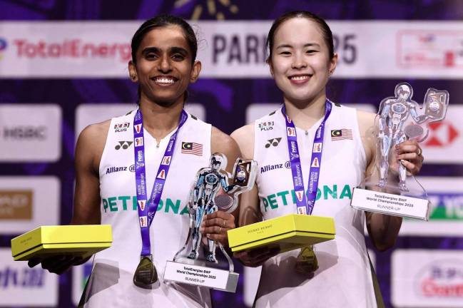 Silver medal winner Malaysia’s Thinaah Muralitharan and Pearly Tan celebrate on podium with their medals and trophies following the women’s doubles final match at the Badminton BWF World Championships at the Adidas Arena in Paris. - AFP pic
