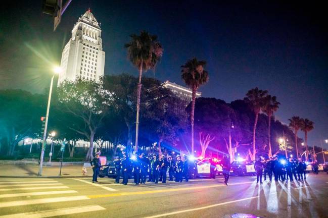 Police officers in riot gear stand near City Hall as a curfew is in effect following days of protests in response to federal immigration operations in Los Angeles on June 10, 2025. An overnight curfew went into effect in protest-hit downtown Los Angeles on June 10, with Mayor Karen Bass earlier saying it was to “stop the vandalism, to stop the looting” after several days of unrest.