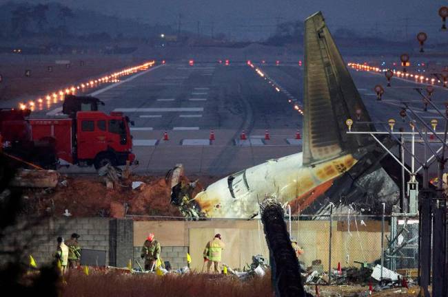 FILE PHOTO: Rescuers work near the wreckage of the Jeju Air aircraft that went off the runway and crashed at Muan International Airport, in Muan, South Korea, December 30, 2024. - REUTERS/Kim Hong-Ji/File Photo