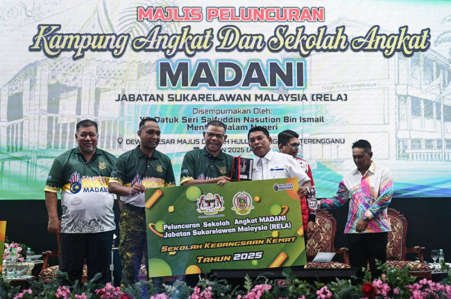 Home Minister Datuk Seri Saifuddin Nasution Ismail (center) presents the MADANI Adopted School launch plaque to the Headmaster of Sekolah Kebangsaan Kemat, Zamri Juhari (second from right) at the Launch Ceremony of the 2025 MADANI Adopted Village and School Program by the Malaysian Volunteer Department (RELA) held at the Grand Hall of the Hulu Terengganu District Council yesterday. - BERNAMA