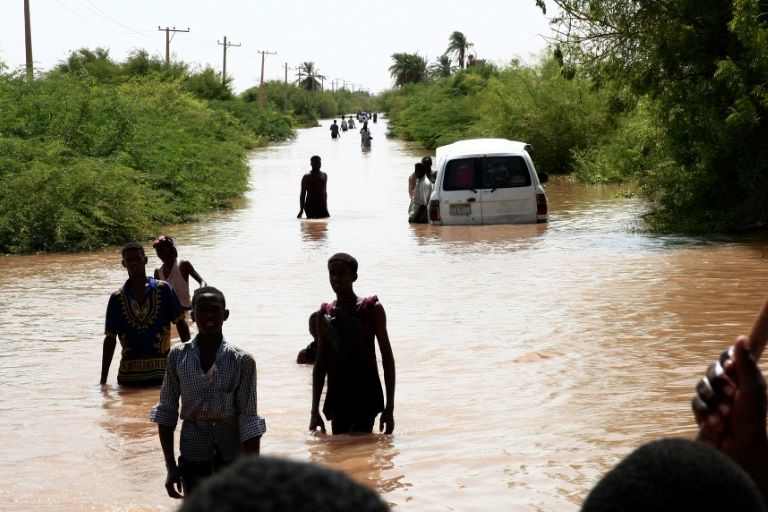 Sudanese people walk a flooded road in Wad Ramli village on the eastern banks of the Nile river. — AFP