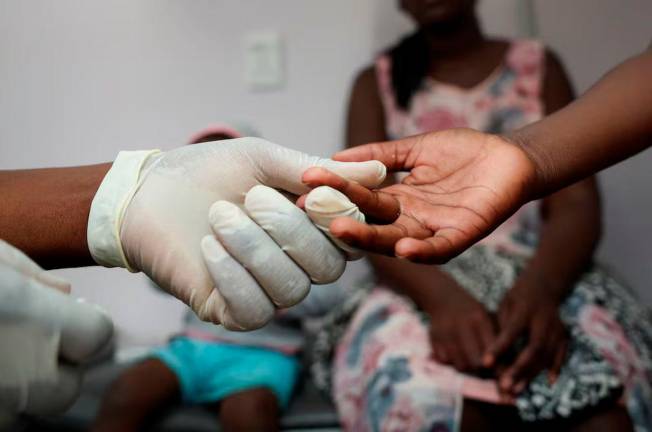 A nurse takes a blood sample from a child for an HIV test while the child’s mother looks on at a clinic in Diepsloot, north of Johannesburg, South Africa, March 12, 2025. REUTERS/Siphiwe Sibeko