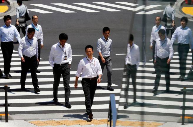 For representational purposes: Office workers are reflected in a glass railing as they cross a street during lunch hour in Tokyo. REUTERSpix