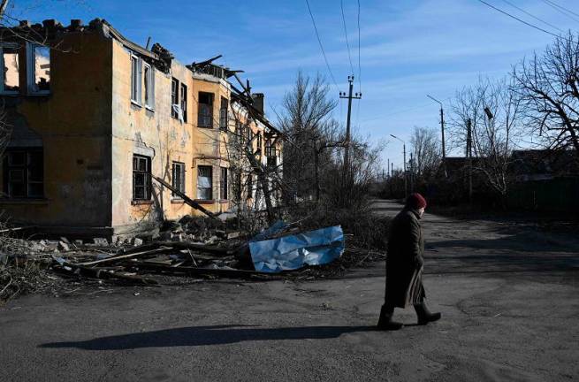 A local resident walks past a heavily damaged building in Kostyantynivka, near the front line in the Donetsk region, on February 14, 2025, amid the Russian invasion of Ukraine. - Genya SAVILOV / AFP