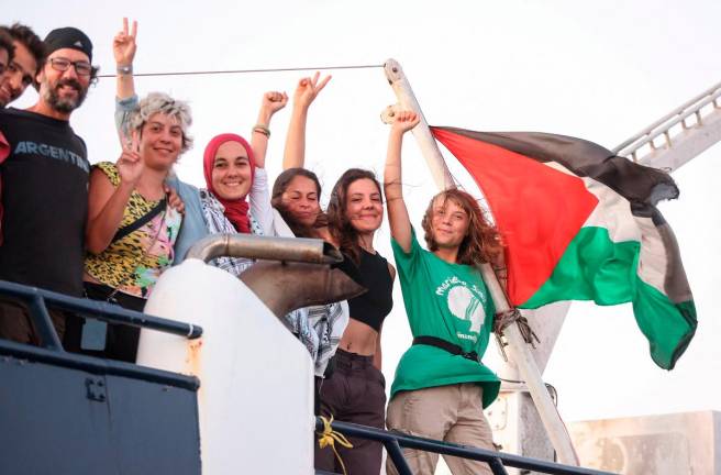 Greta Thunberg and other crew members flash victory signs from their ship, part of the Global Sumud Flotilla aiming to reach Gaza and break Israel’s naval blockade, as they sail off Crete island, Greece, September 25, 2025. - REUTERS