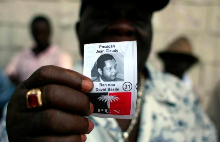 A former member of Tonton Macoute paramilitary force displays a photograph of Jean-Claude “Baby Doc” Duvalier while on guard outside a private hospital in Port-au-Prince where the ex-dictator was being treated in 2011. — AFP