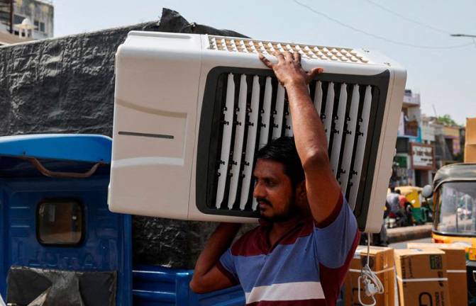FILE PHOTO: A worker carries an air cooler for delivery to a customer during the heat wave in Ahmedabad, India, May 30, 2024. REUTERSpix