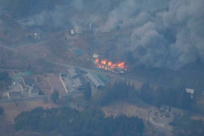 An aerial views shows a building on fire due to the spread of a wildfire in Ofunato, Iwate Prefecture, northeastern Japan, February 28, 2025, in this photo taken by Kyodo. - Kyodo/via REUTERS