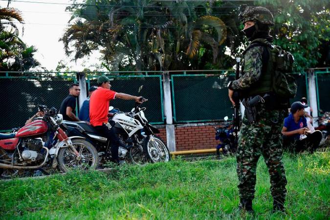 Colombian army soldiers stand guard next to displaced people from recent clashes between armed groups arriving in the municipality of Tibu, Norte de Santander Department, Colombia, on January 18, 2025. At least 39 people have been killed in violence involving leftwing guerillas near Colombia’s restive border with Venezuela, authorities said Friday, prompting the government to suspend high-stakes peace talks with the group. - Schneyder Mendoza / AFP